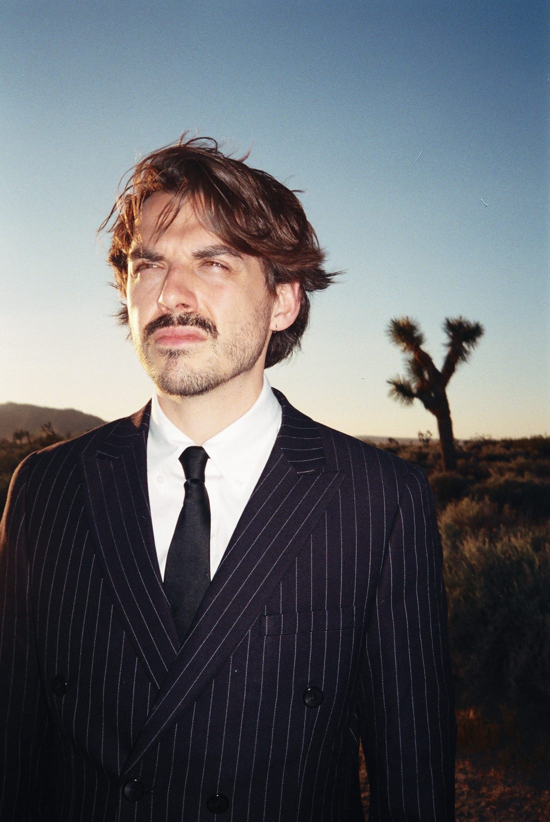 Portrait of Guillaume Banet in a pinstripe suit in the desert